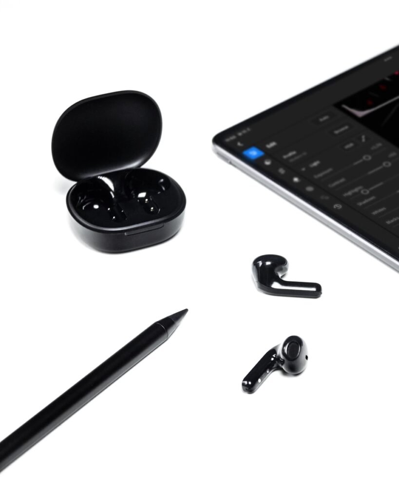 A tablet, pen, earbuds, and a pair of earbuds