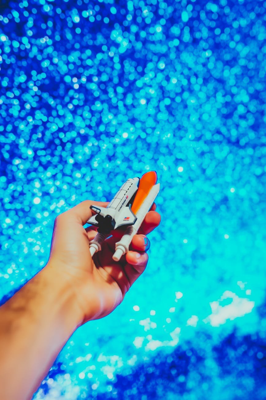 orange and white rocket ship held by a man, toy rocket
